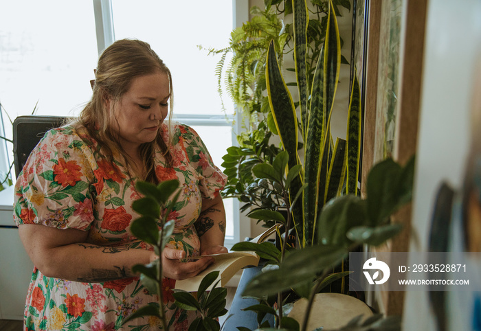 woman reads book surrounded by plants