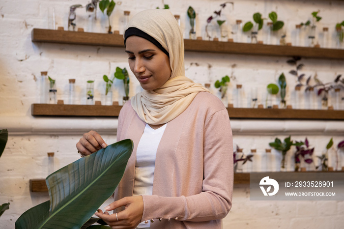 Woman wearing headscarf looking at banana leaf in flower shop