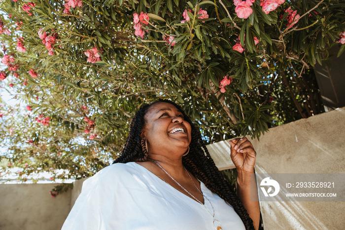 plus size African American woman smelling and looking at pink flowers