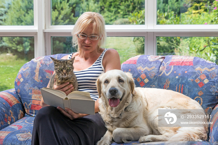 Middle age woman is reading a book with pets together