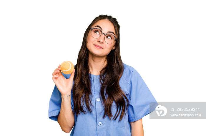 Young caucasian physiotherapist woman holding a tennis ball isolated isolated on green chroma background dreaming of achieving goals and purposes