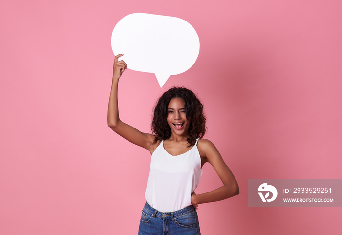 Smiling happy african woman holding blank speech bubble and looking at the camera on pink  background.