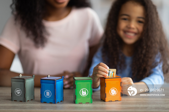 Eco education concept. African American woman playing environmental board game with her daughter, copy space