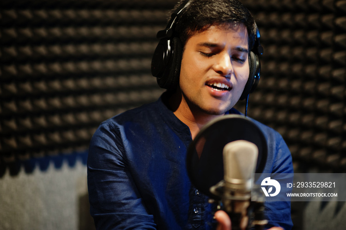 Young asian singer man with microphone recording song in record music studio.