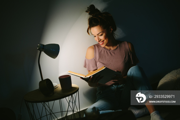 Young pretty woman sitting on floor, relaxing at home and enjoy reading book.