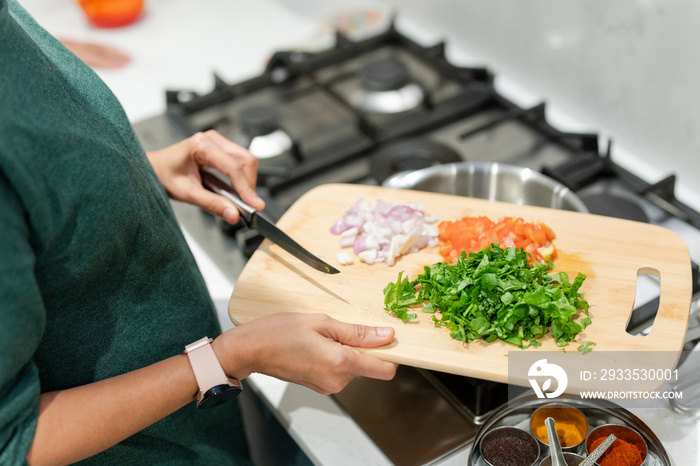 Woman holding cutting board with chopped vegetables