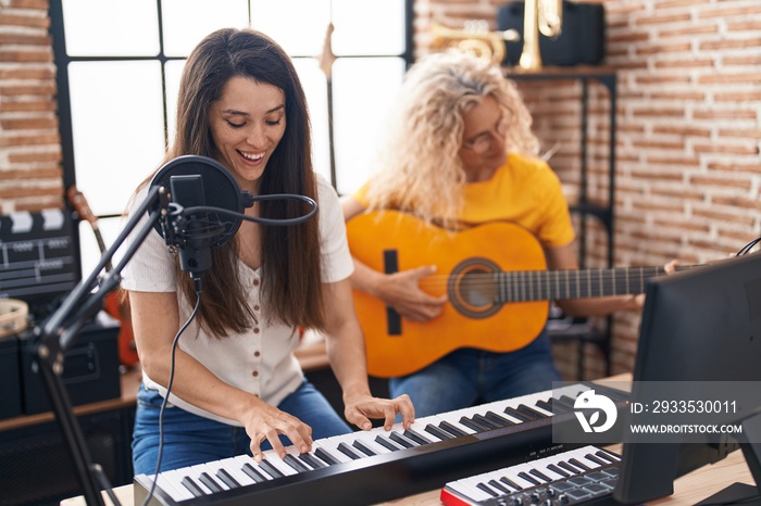 Two women musicians singing song playing classical guitar and piano at music studio