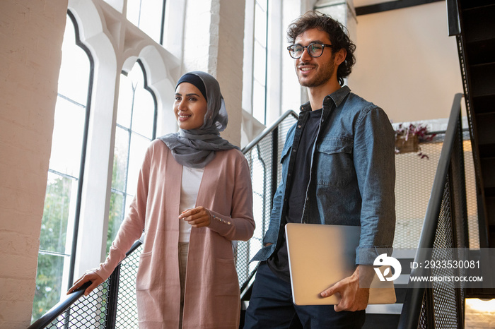 Smiling woman wearing headscarf and man on steps