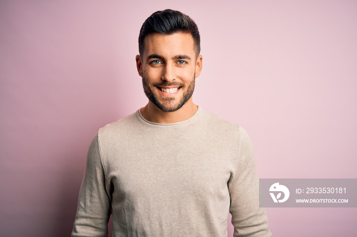 Young handsome man wearing casual sweater standing over isolated pink background with a happy and cool smile on face. Lucky person.