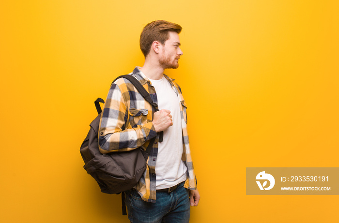 Young redhead student man on the side looking to front