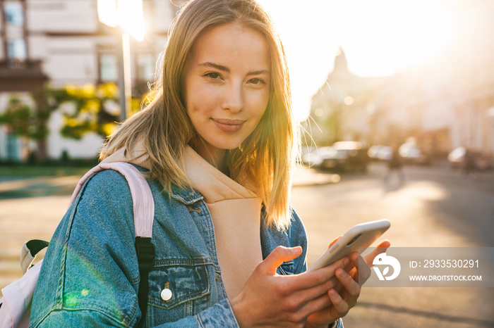 Cheerful young blonde girl using mobile phone