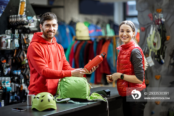 Portrait of a young woman as a customer with salesman at the counter of the sports shop