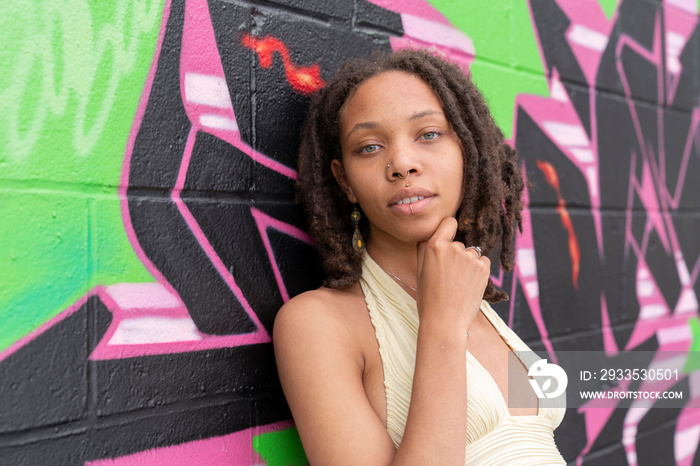 Portrait of young woman against graffiti wall