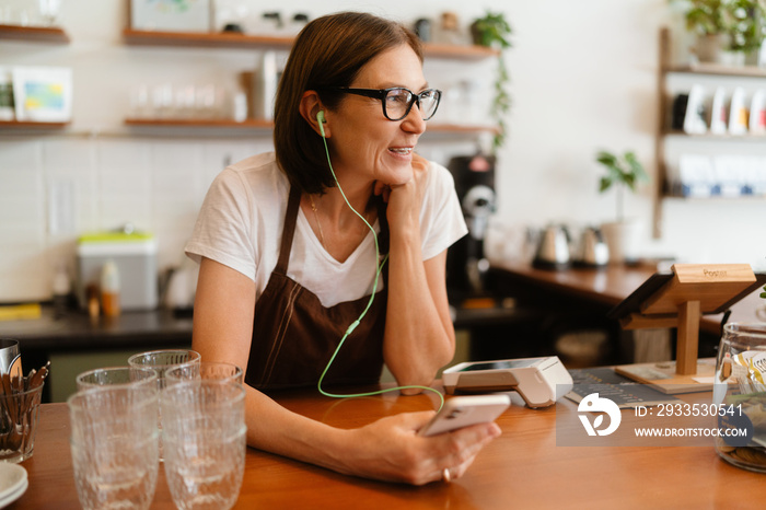 White mature barista woman smiling while working in cafe