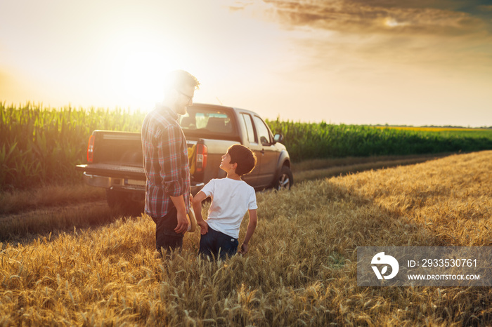 father and son walking through wheat field