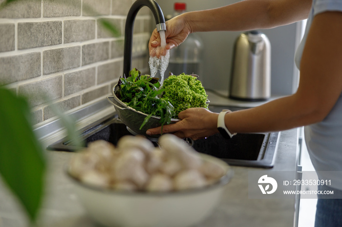 Beautiful smily handsome woman is preparing tasty fresh healthy salad at her kitchen at home