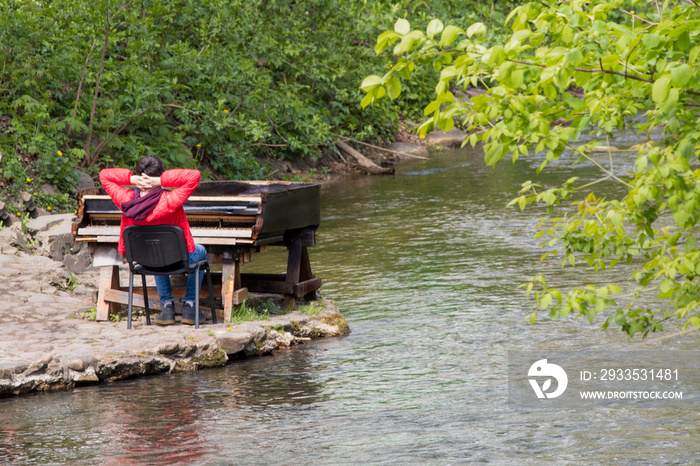 man in red jacket relax piano on river