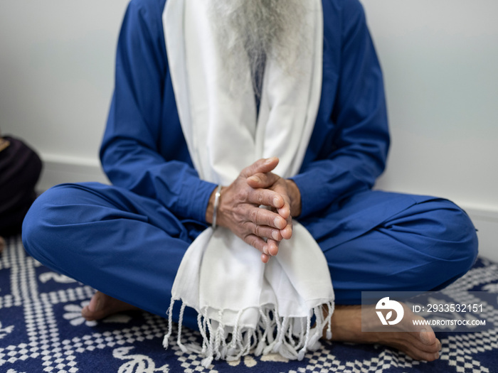 Senior man in traditional clothing praying at home