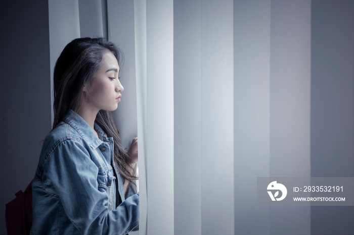 Unhappy teenage girl looking out the window