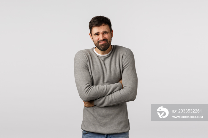 Man ate street food, poisoned, feeling unwell. Bearded guy grey sweater feeling discomfort in stomach, hug himself as suffer stomachache, grimacing displeased, have disorder, sick, white background