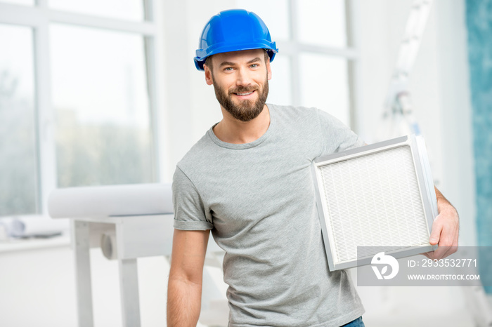 Worker holding air filter for installing in the house ventilation system. Purity of the air concept