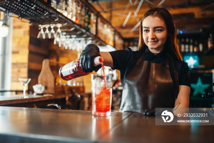 Female barman prepares alcoholic coctail with ice