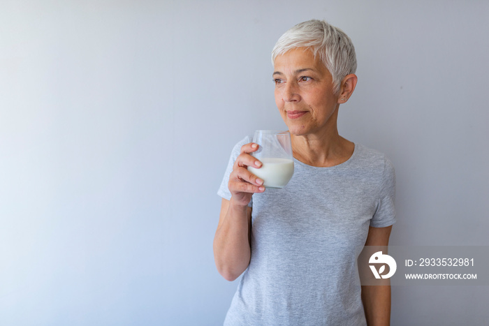 Senior woman drinking a glass of fresh milk serious face. Senior Woman Holding Glass Of Milk At Home. Smiling, beautiful senior lady drinking a glass of milk..