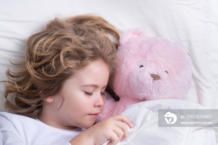 Cute child sleeping with a toy teddy bear on bed at home. Bedtime, kid sleeps. Kid asleep on soft pillow with blanket having healthy sleep.