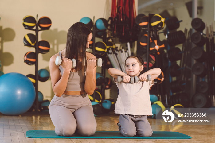 Mom and daughter swing with a dumbbell. Engaged in strength