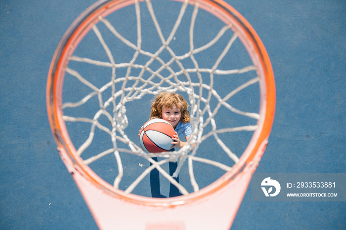 Top view of kid playing basketball holding ball with happy face.