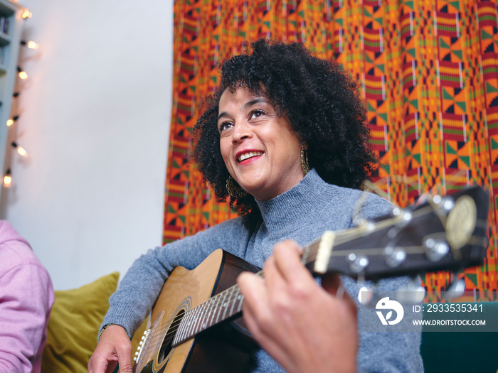 Woman playing acoustic guitar at home