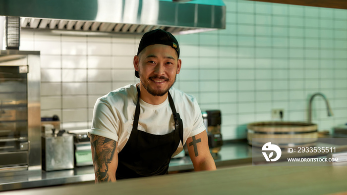 Asian man smiling while standing in the kitchen