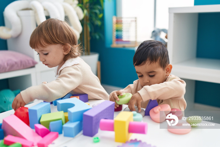 Two kids playing with construction blocks standing at kindergarten