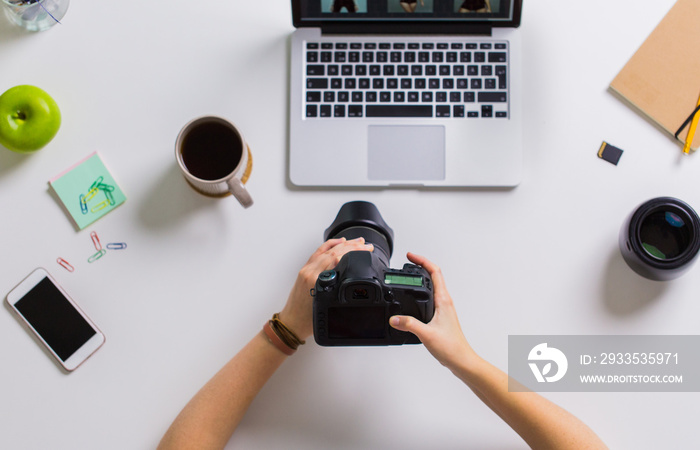 woman hands with camera working on laptop at table