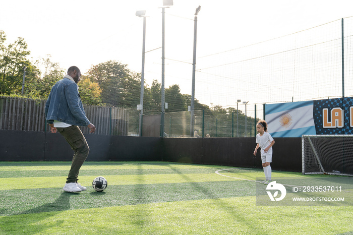 Father and daughter (6-7) playing soccer on soccer field