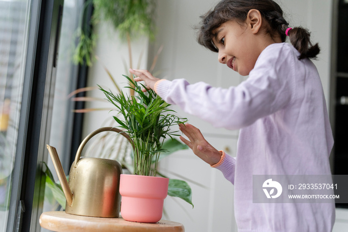 Little girl taking care of plant at home