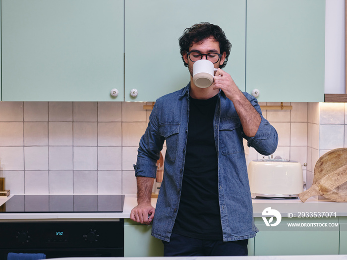 UK, London, Man drinking from mug in kitchen