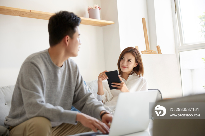 young asian couple working relaxing conversing at home