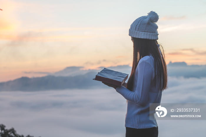 Woman holding reading Bible on Mountain in the Morning- Image