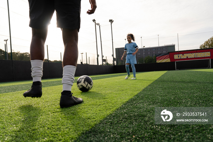 Man and girl (6-7) playing soccer on soccer field