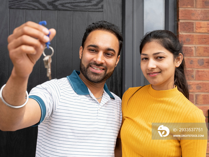 Portrait of smiling couple holding keys to house