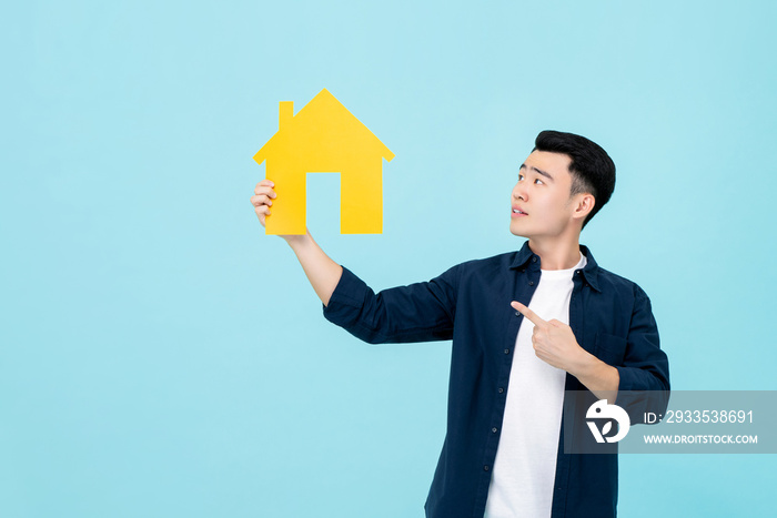 Young Asian man holding and pointing to house cut out