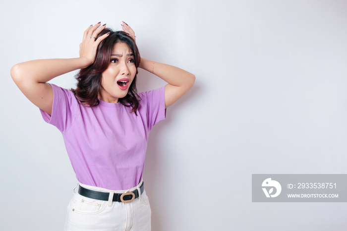 A portrait of a shocked Asian woman wearing a lilac purple t-shirt, isolated by a white background