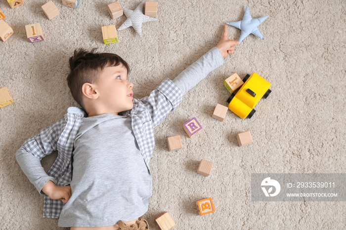 Little boy with toys lying on floor, top view