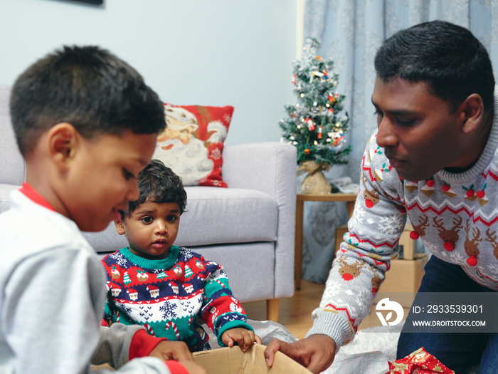 Father and sons opening Christmas presents