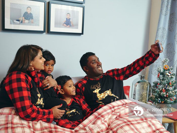 Parents with sons sitting in bed and taking selfie