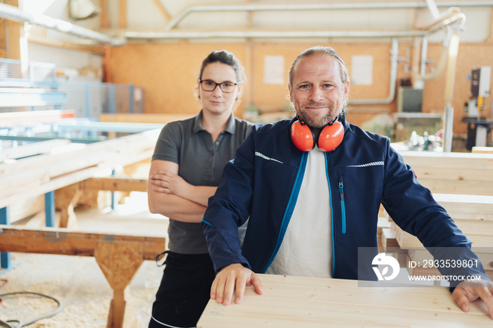 Smiling carpenter with female colleague in a woodworking factory