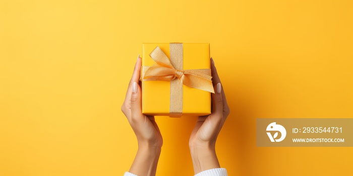 christmas background with hands holding present box on a Yellow background.