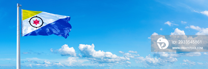 Bonaire flag waving on a blue sky in beautiful clouds - Horizontal banner