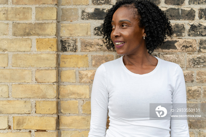 Portrait of smiling woman standing by brick wall